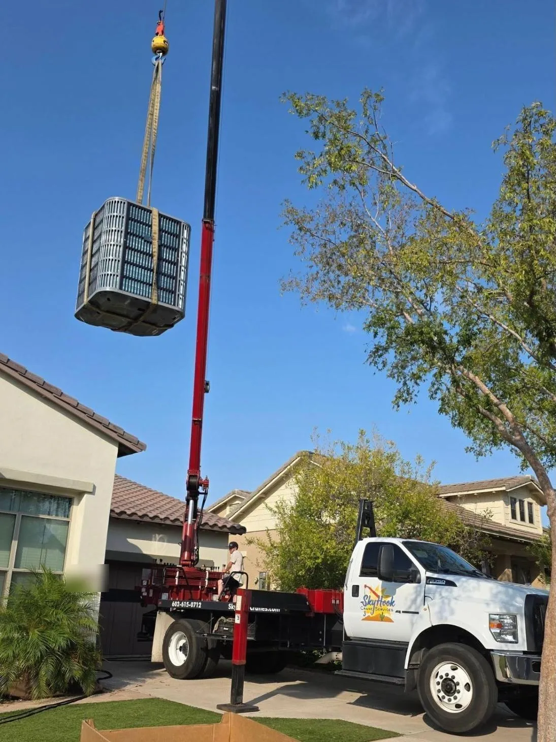Crane lifting an AC condenser over a two-story home in the West Valley