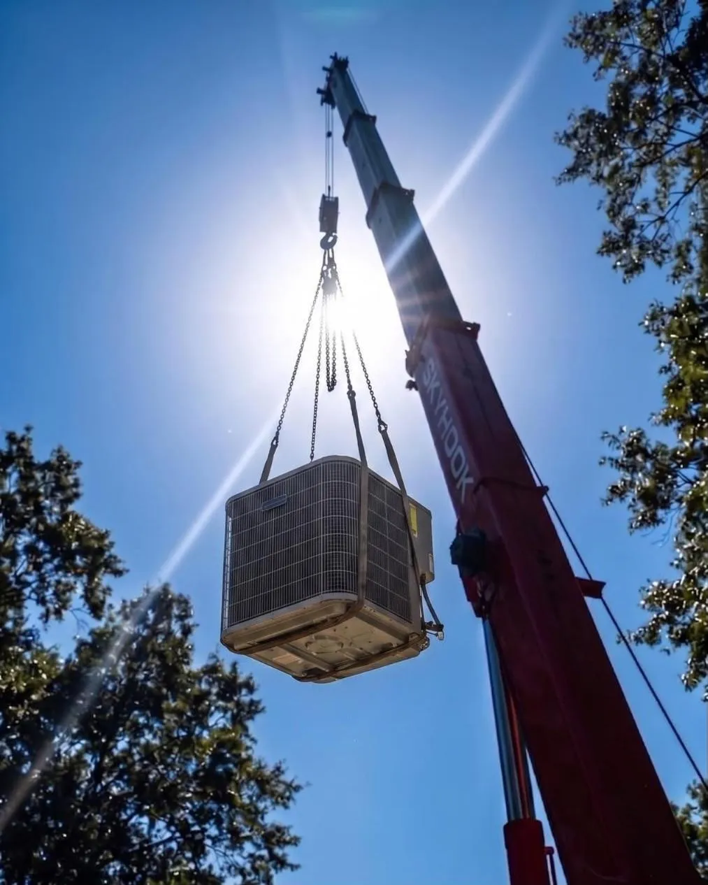 AC condenser lifted on chain rigging against the Arizona sun