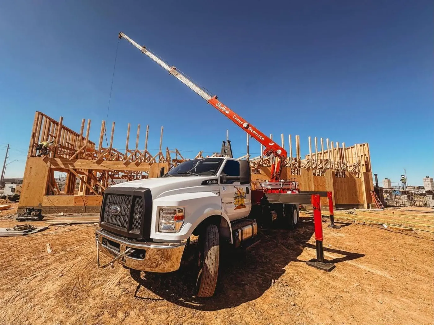 Skyhook crane lifting materials on a wood-frame construction site