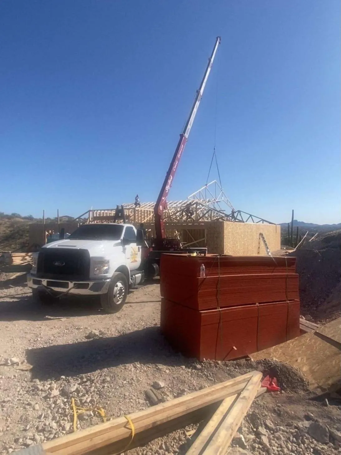 Crane setting roof trusses on a new home in the Arizona desert
